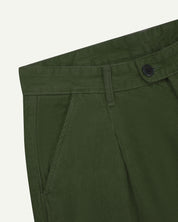 Close up of waist area of Uskees cord boat pants in coriander green. Clear view of front pocket, belt loops and Corozo button fastening.