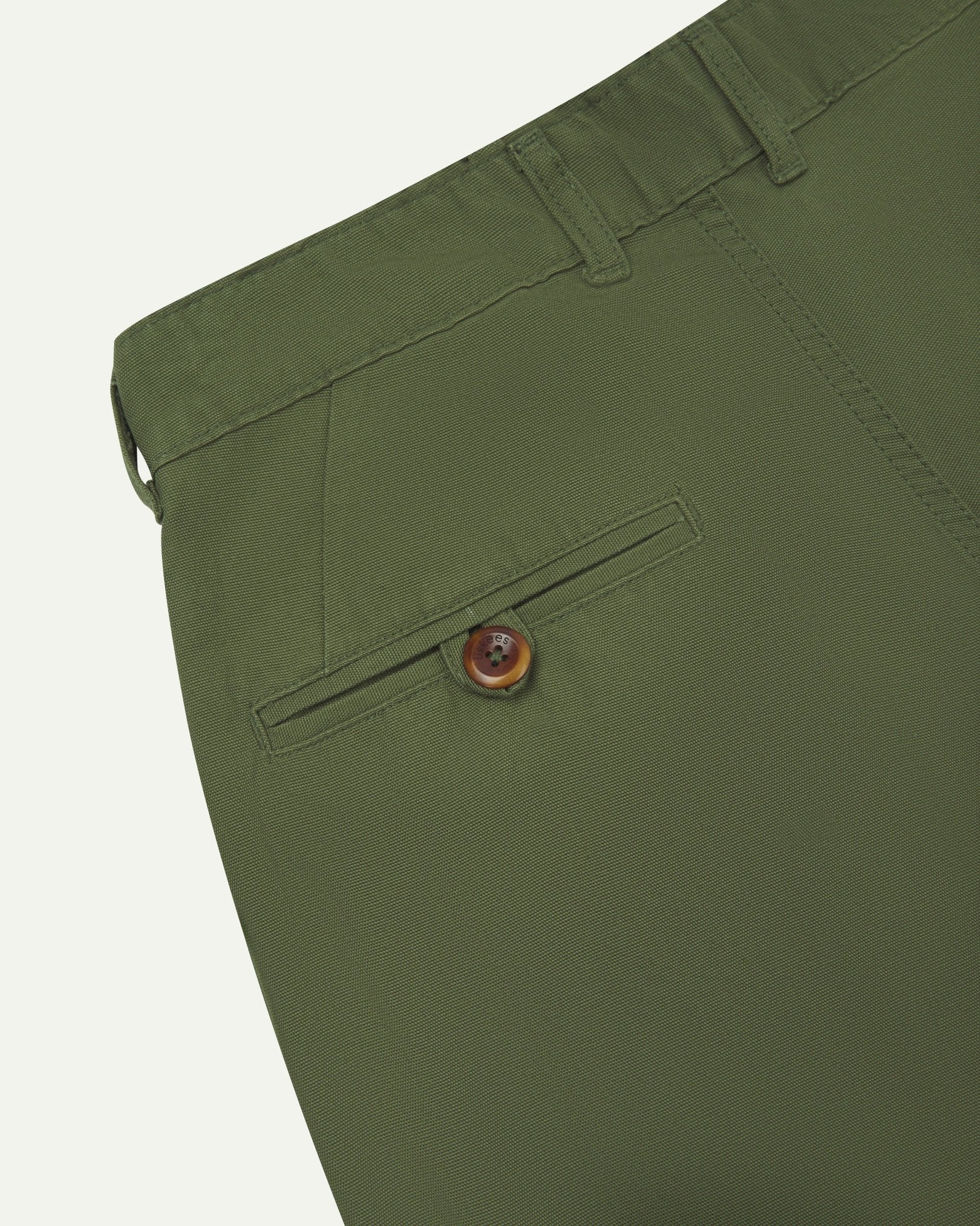 Back close-up view of 5018 Uskees men's organic mid-weight cotton boat trousers in coriander-green showing belt loops and buttoned back pocket.