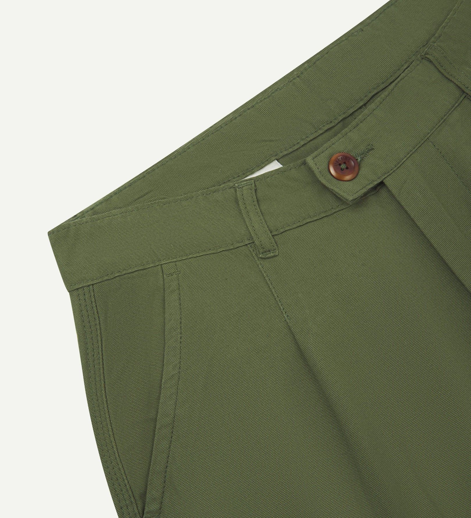 Front close-up shot of 5018 Uskees men's organic mid-weight cotton boat trousers in coriander-green showing corozo button fastening at waistband, belt loops and front pocket.