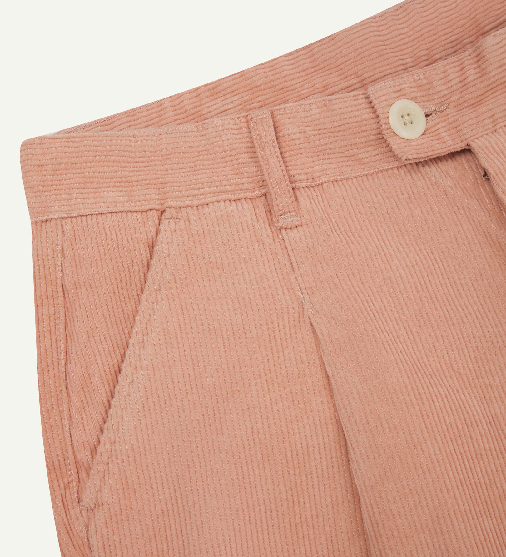 Close up of waist area of Uskees cord boat pants in dusty pink. Clear view of front pocket, belt loops and Corozo button fastening.
