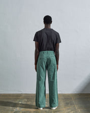 Full length back-view of model wearing eucalyptus-green corduroy #5018 trousers with view of rear pockets and belt loops and demonstrating vintage wide leg fitting.