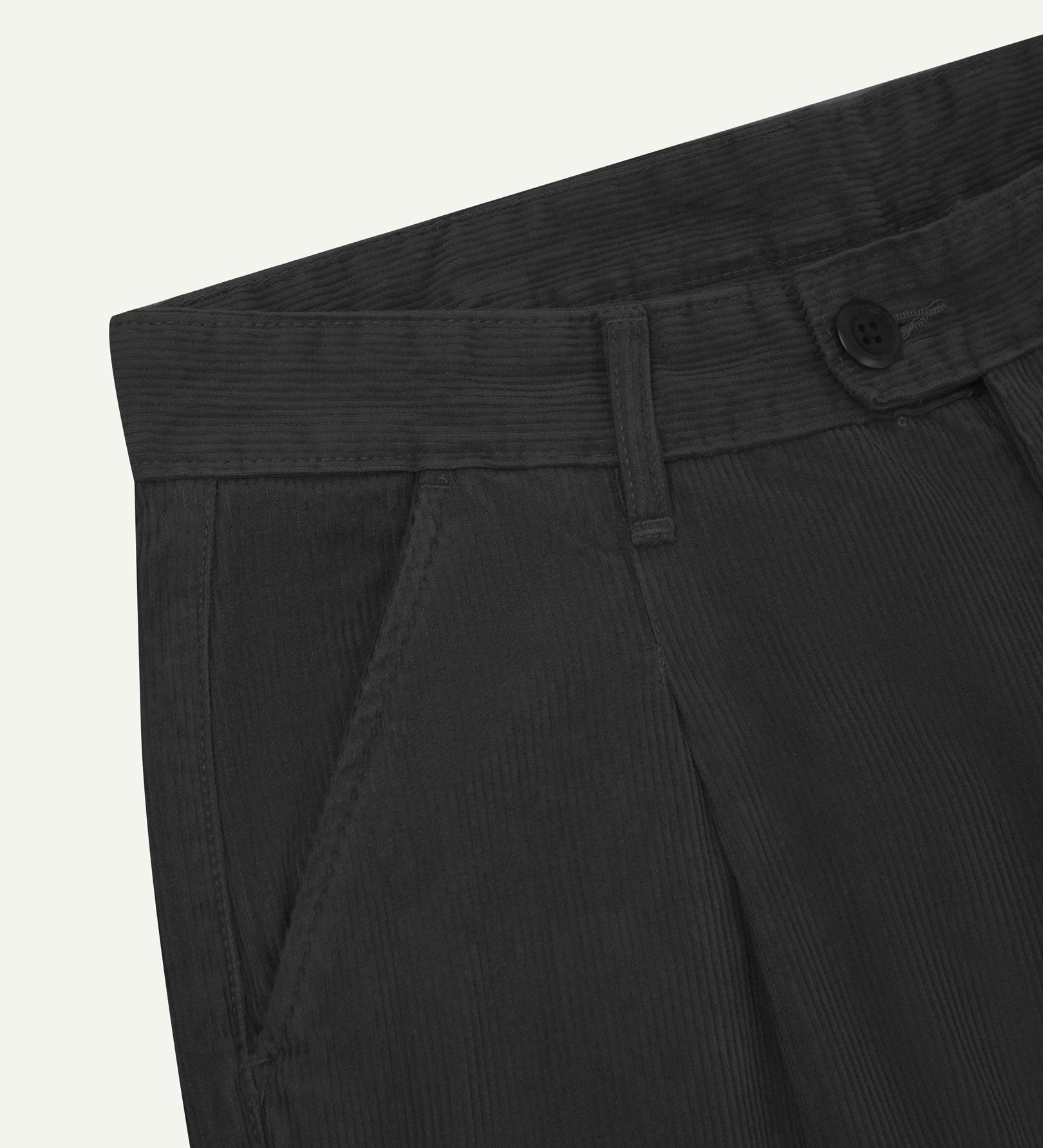 Close up of waist area of Uskees cord boat pants in faded black. Clear view of front pocket, belt loops and Corozo button fastening.