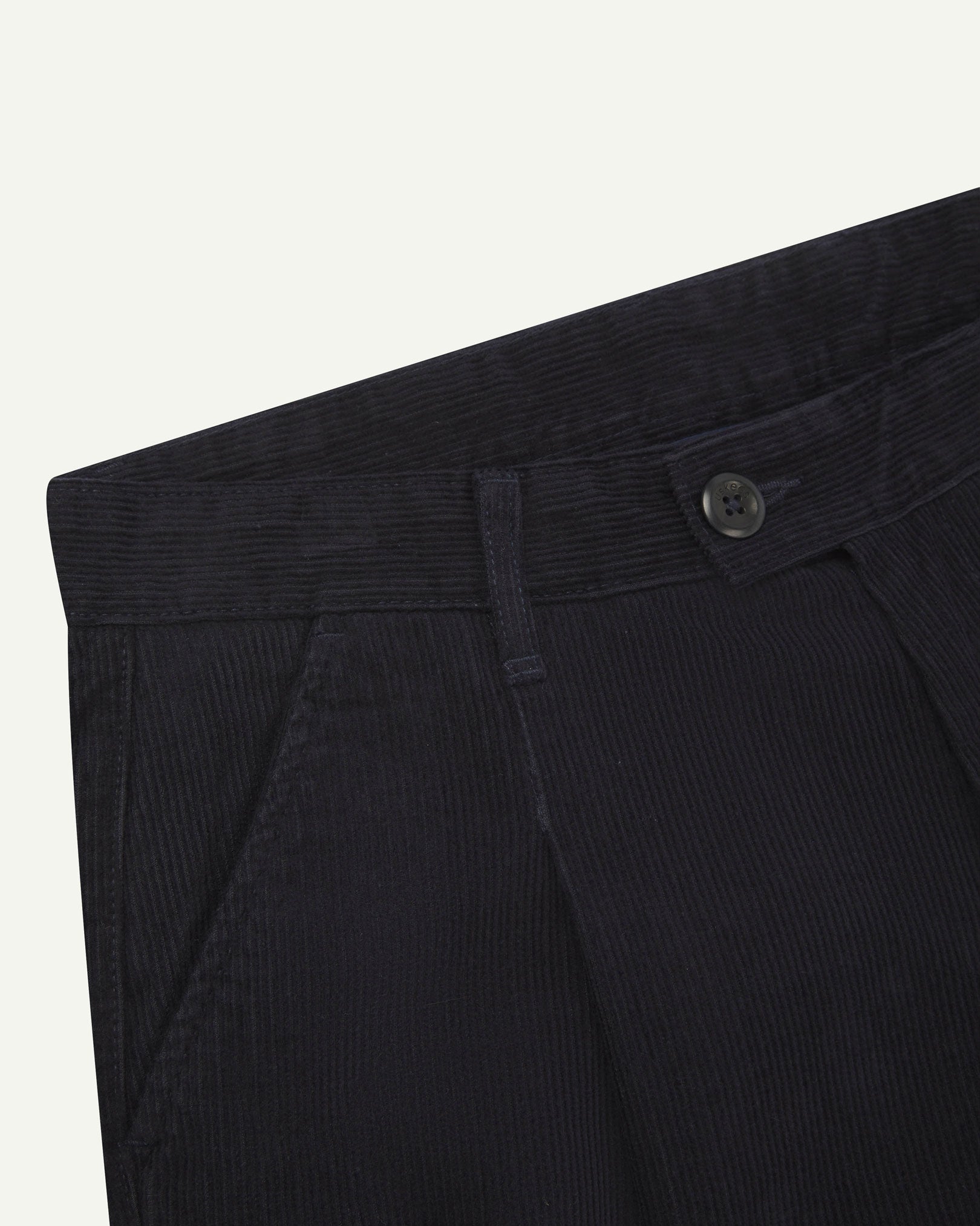 Close up of waist area of Uskees cord boat pants in midnight blue. Clear view of front pocket, belt loops and Corozo button fastening.