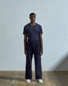 Full length front-view of model wearing midnight blue corduroy #5018 trousers with view of corozo button fastening. Paired with matching Uskees t-shirt.