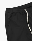 Close up front view of the front pocket, elasticated waist and tie of the black ripstop pants from Uskees.