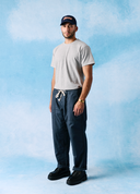 Front view of model wearing  5020 ripstop utility pants in blueberry. Indicating drawstring, tapered fit on the leg, deep front pockets and reinforced knee patches. 