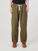 Front view of model wearing  5020 ripstop utility pants in ivy green. Indicating drawstring, tapered fit on the leg, deep front pockets and reinforced knee patches. 