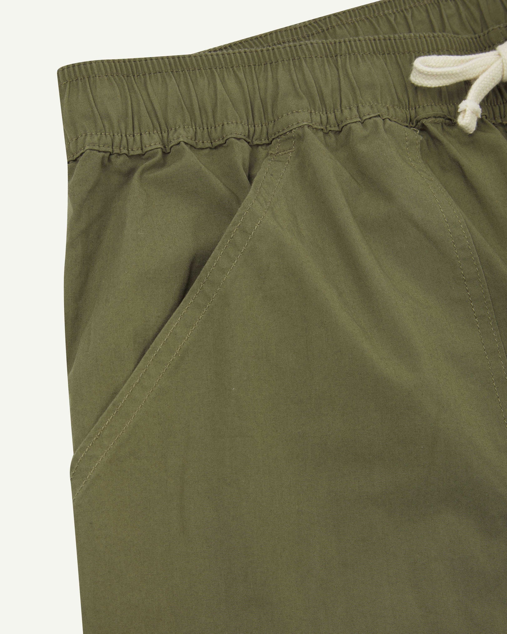 Front close-up shot of Uskees 5020 lightweight utility pants in olive-green showing waist and front pocket detail.