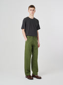 Full-length view modelling 5021 Uskees men's organic twill coriander-green painter pants paired with black Uskees T-shirt.