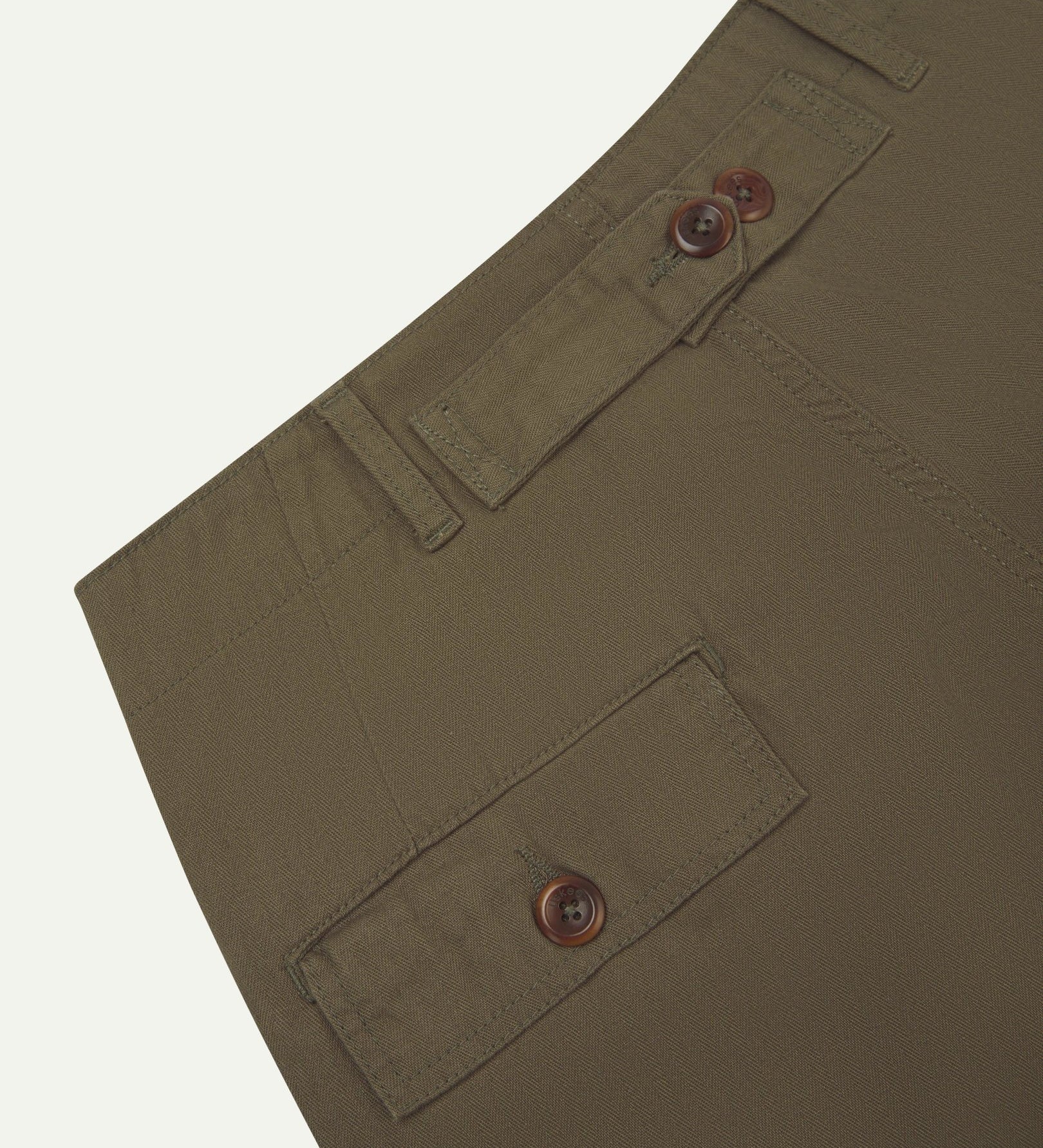 Close up, angled back view of Uskees 5022 barrel leg pants in dark taupe with focus on cinch strap, neat back pocket with flap, belt loops and durable herringbone fabric.