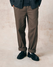 Closer front view of model wearing dark taupe 5022 barrel leg pants from Uskees, illustrating 'mid-rise' cut.