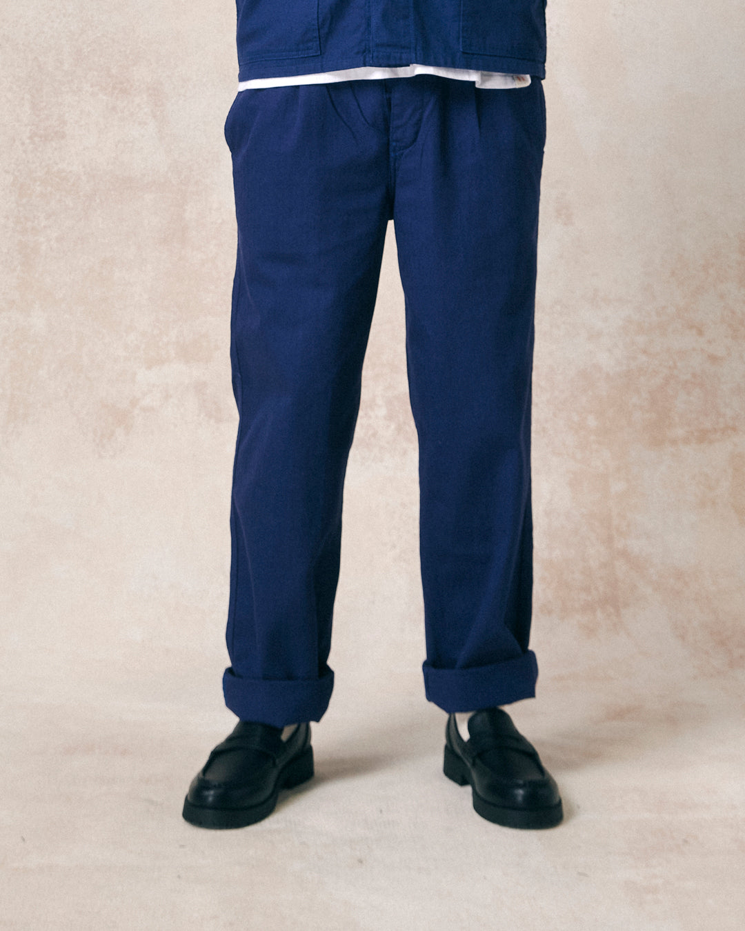 Closer front view of model wearing deep indigo 5022 barrel leg pants from Uskees. Showing button fly and herringbone textured fabric.