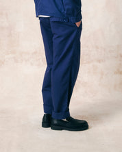 Side view of model wearing deep indigo 5022 barrel leg pants from Uskees. Showing baggy fit with taper at the hem, back pockets with flap and turn-ups.