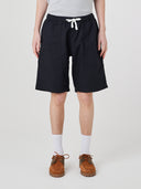 Bottom-half front view of male model wearing black 5024 men's ripstop utility shorts with clear view of deep utility front patch pockets.
