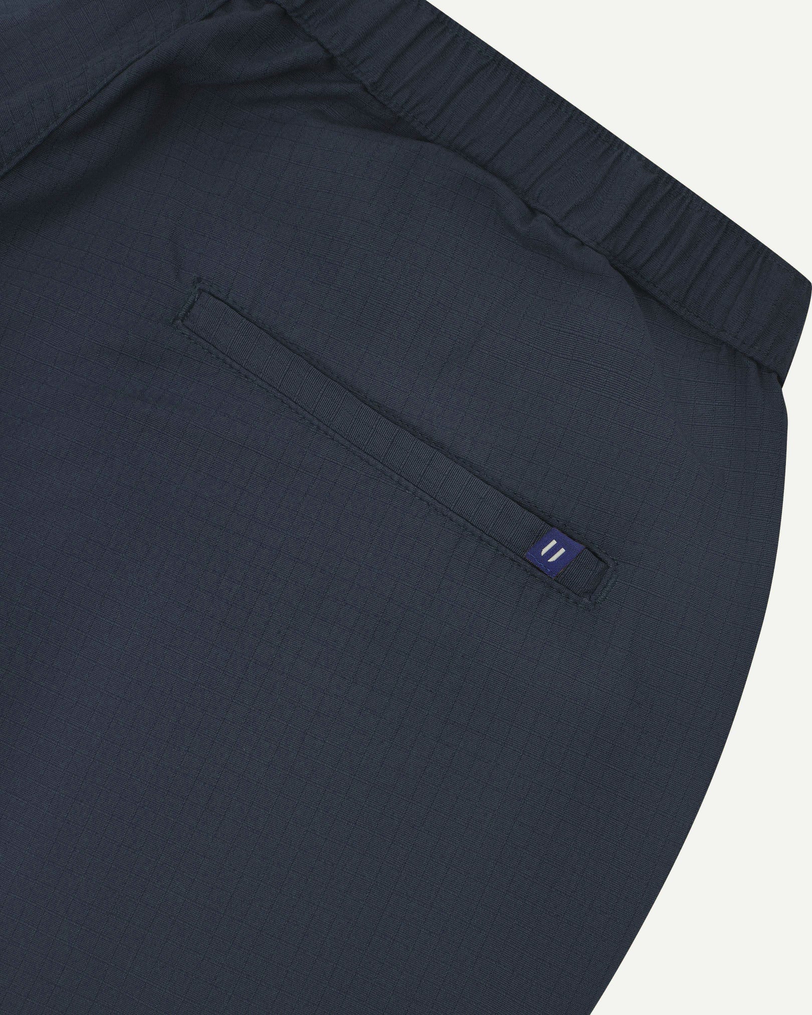 Close-up back view of blueberry 5024 men's ripstop utility shorts. Clear view of jetted back pocket, Uskees logo label and elasticated waistband.