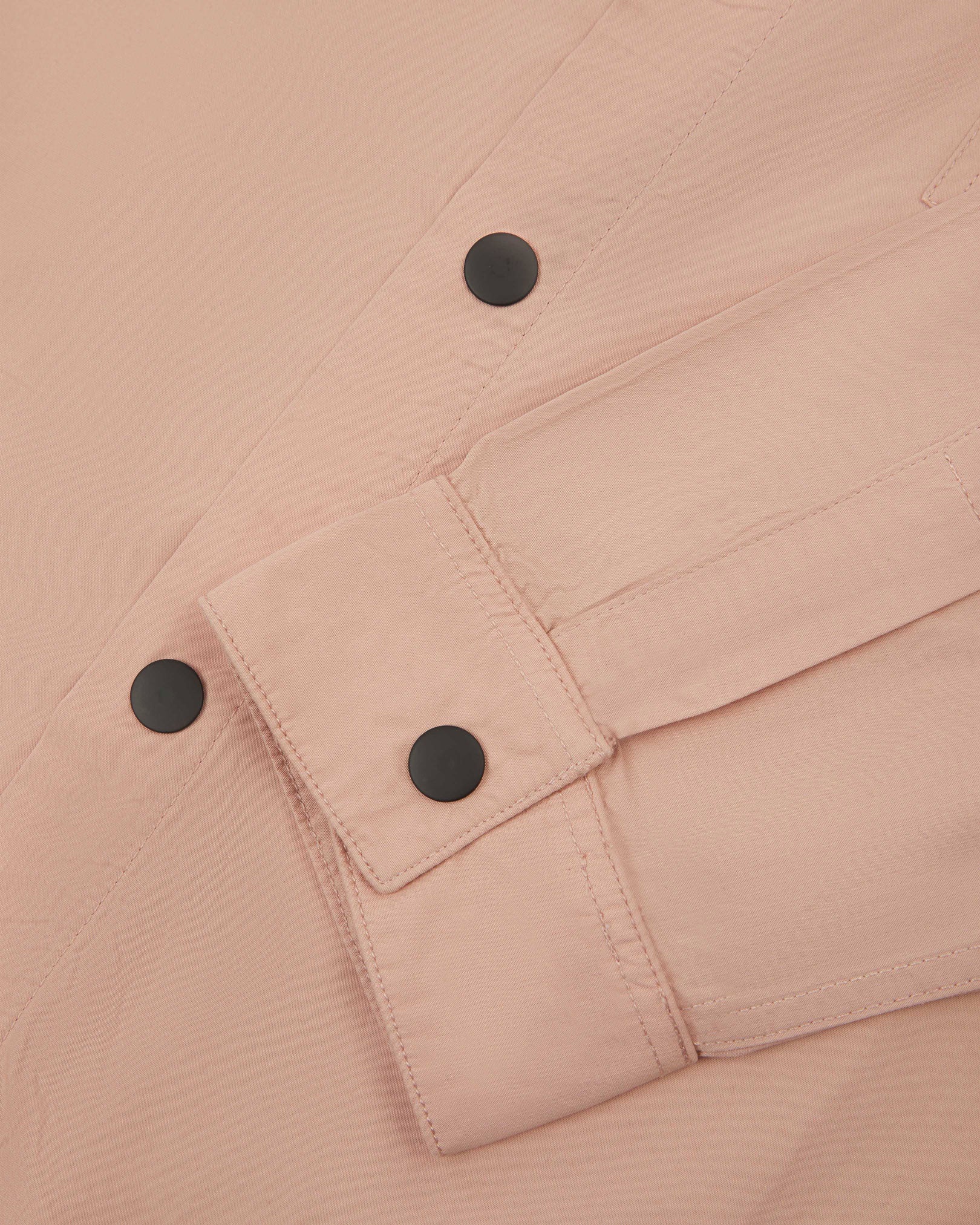 View of the mid-section of the dusty pink 6001 lightweight overshirt from Uskees, with focus on the popper buttons and reinforced cuff, placket and sleeve.