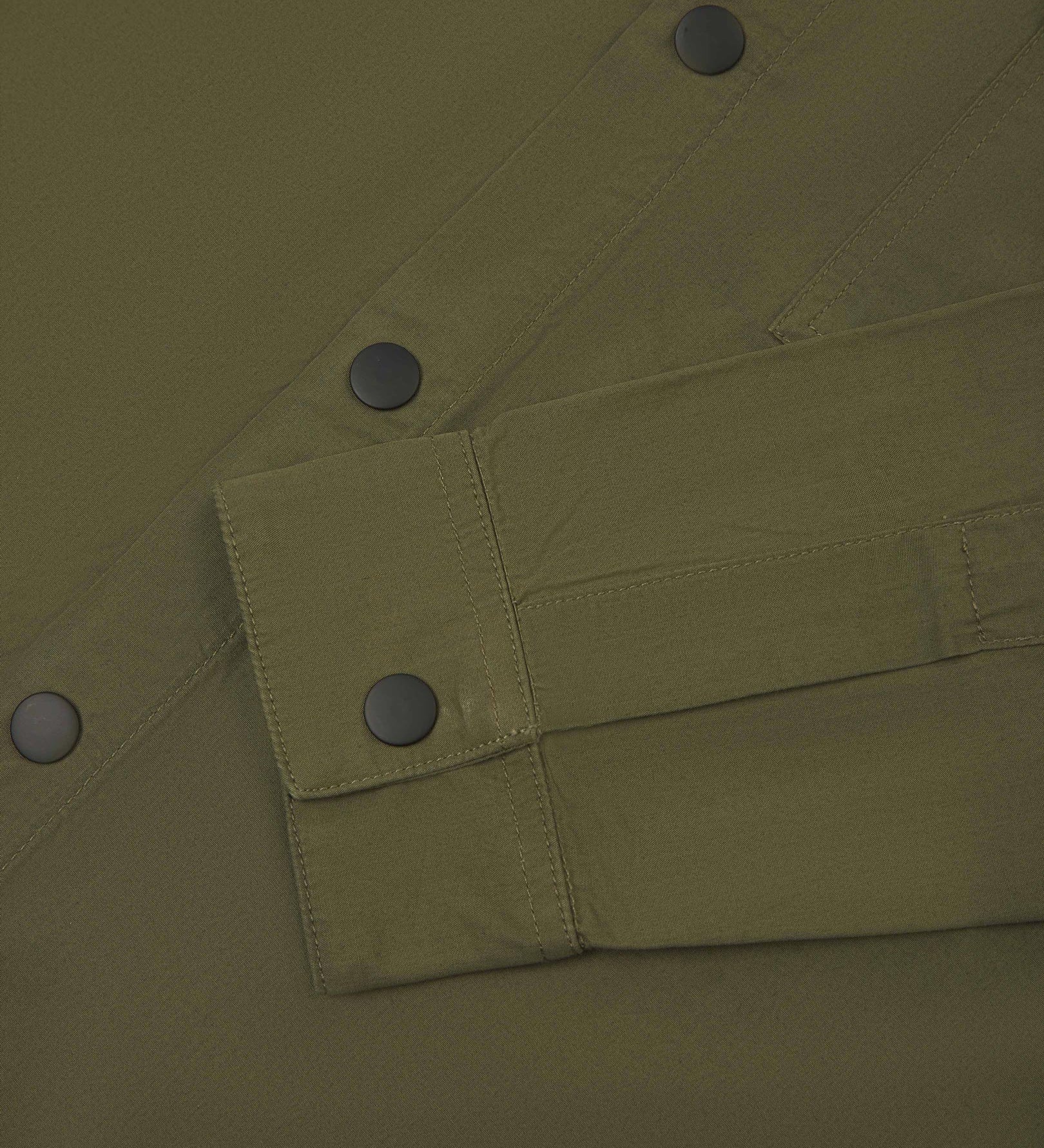View of the mid-section of the olive-green 6001 lightweight overshirt from Uskees, with focus on the popper buttons and reinforced cuff, placket and sleeve.