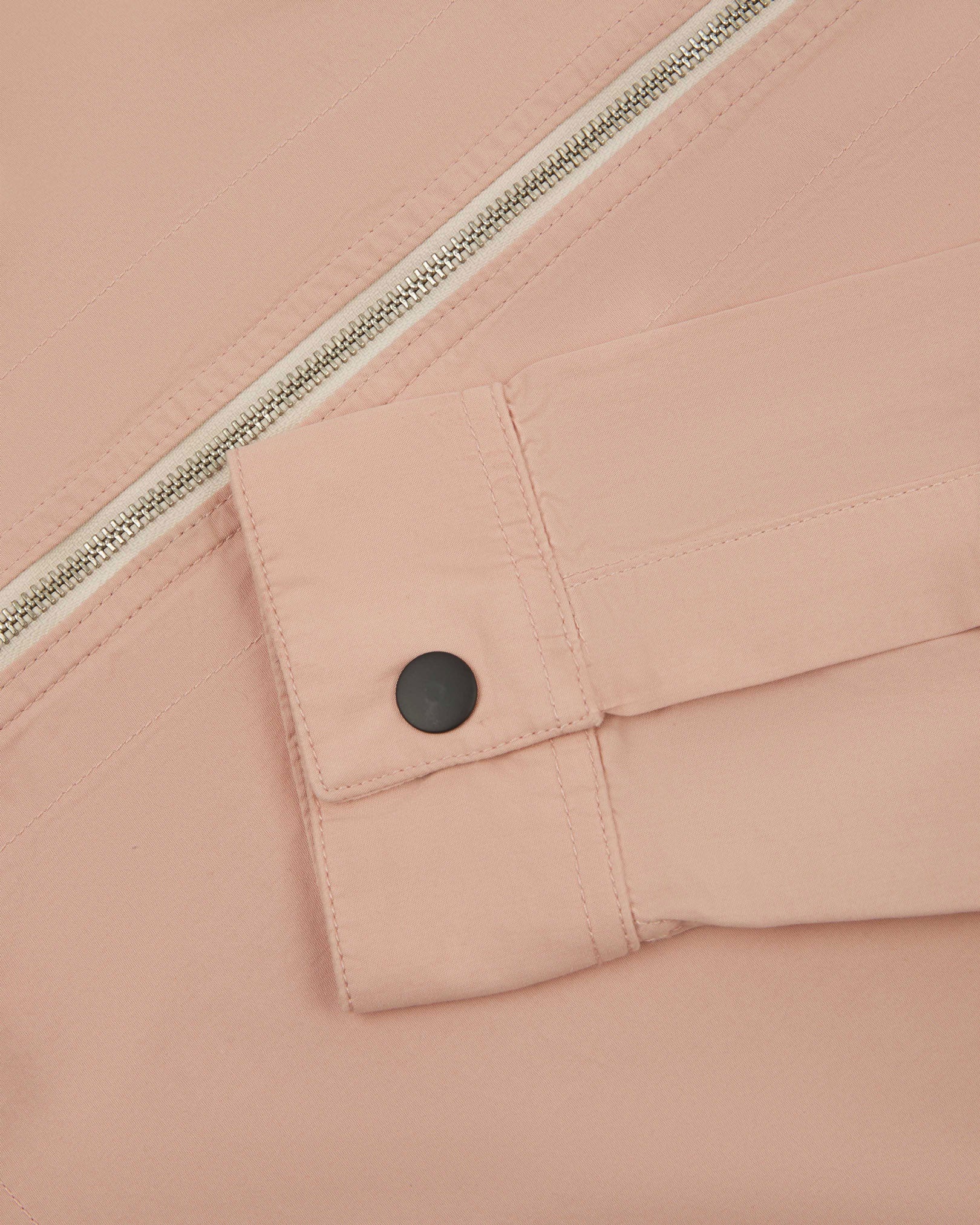 View of the mid-section of the dusty pink 6002 lightweight jacket from Uskees, with focus on the cuff and front zipper detail.