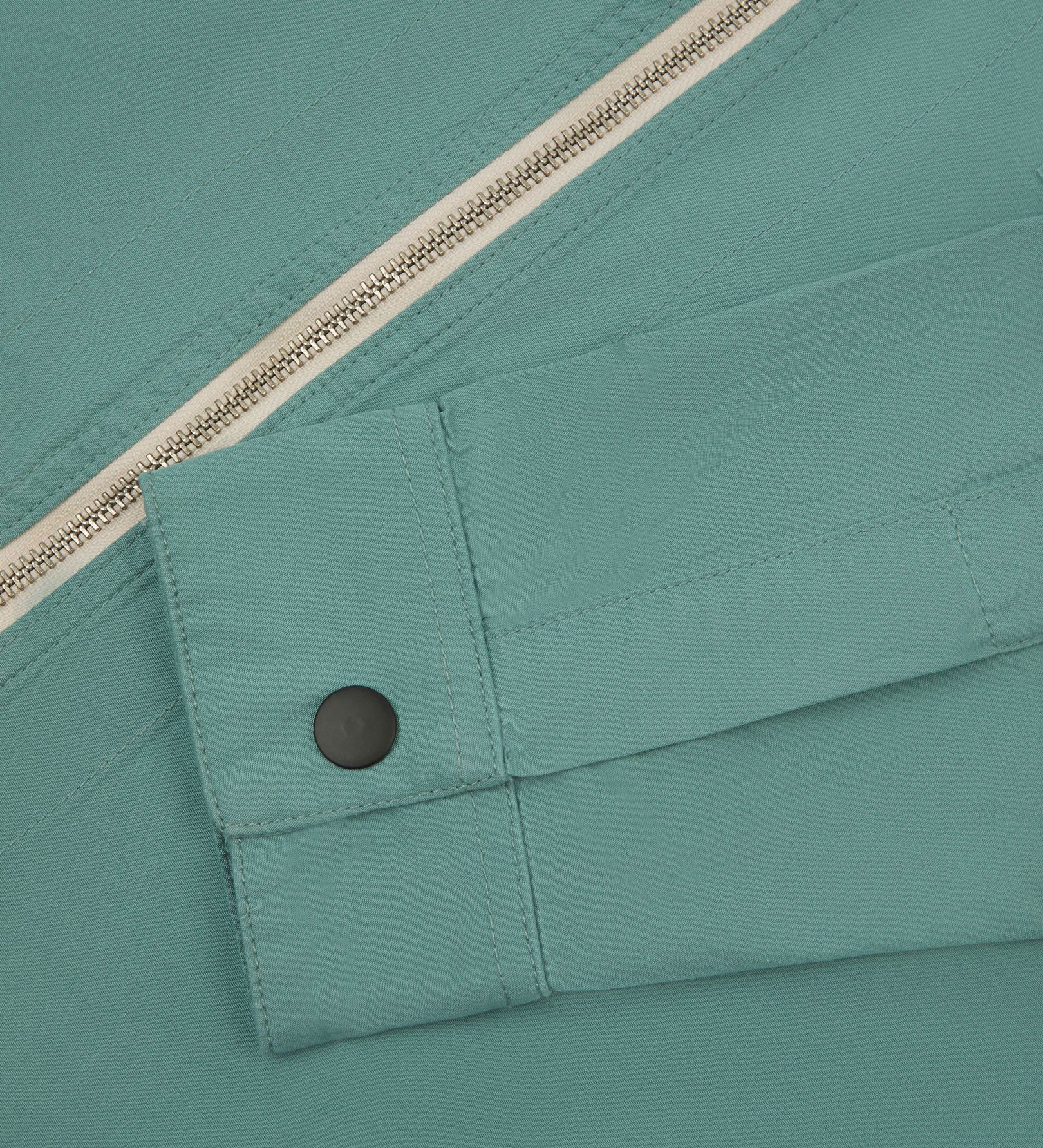 View of the mid-section of the blue-green 'eucalyptus' coloured 6002 lightweight jacket from Uskees, with focus on the cuff and front zipper detail.