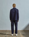 Full-length back view of model wearing Uskees #6002 midnight blue lightweight zip front jacket, showing reinforced elbows and button sleeve placket.