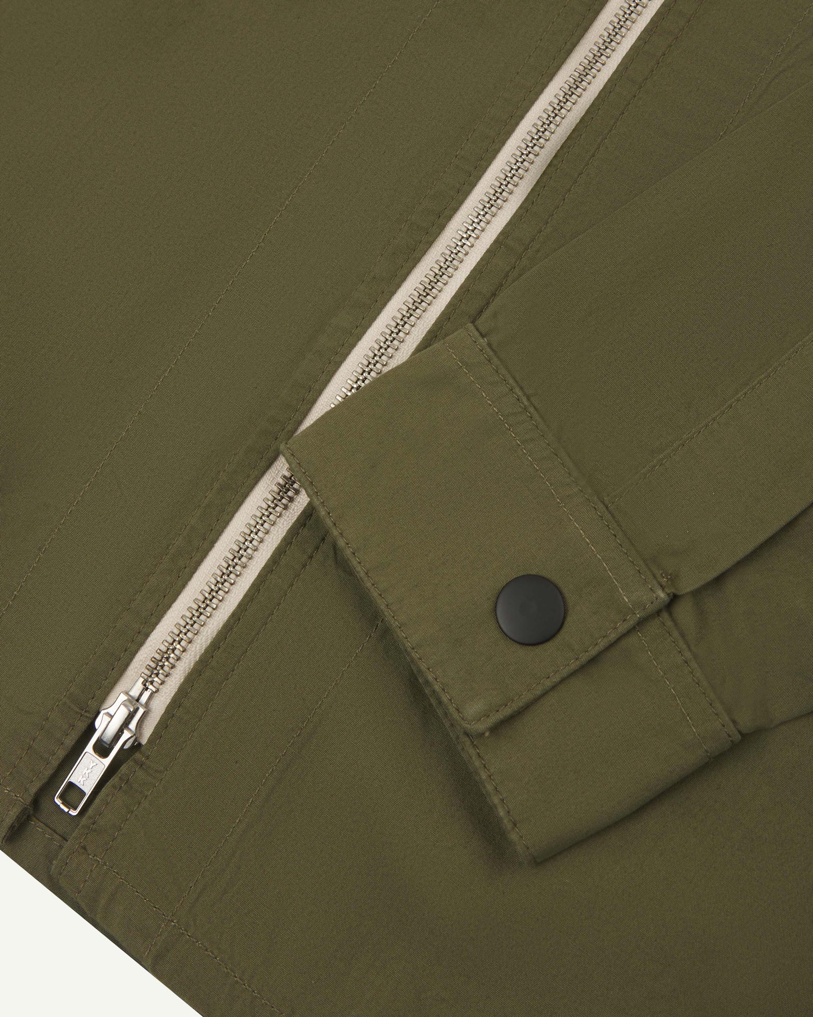 View of the mid-section of the olive-green 6002 lightweight jacket from Uskees, with focus on the cuff and front zipper detail.