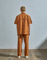Full-length rear view of model wearing #6003 cotton shirt with matching lightweight pale brown pants.