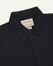 Close-up view of the #6003 reinforced shirt collar, showing weave of midnight blue organic cotton, contrast press studs and Uskees branding label.