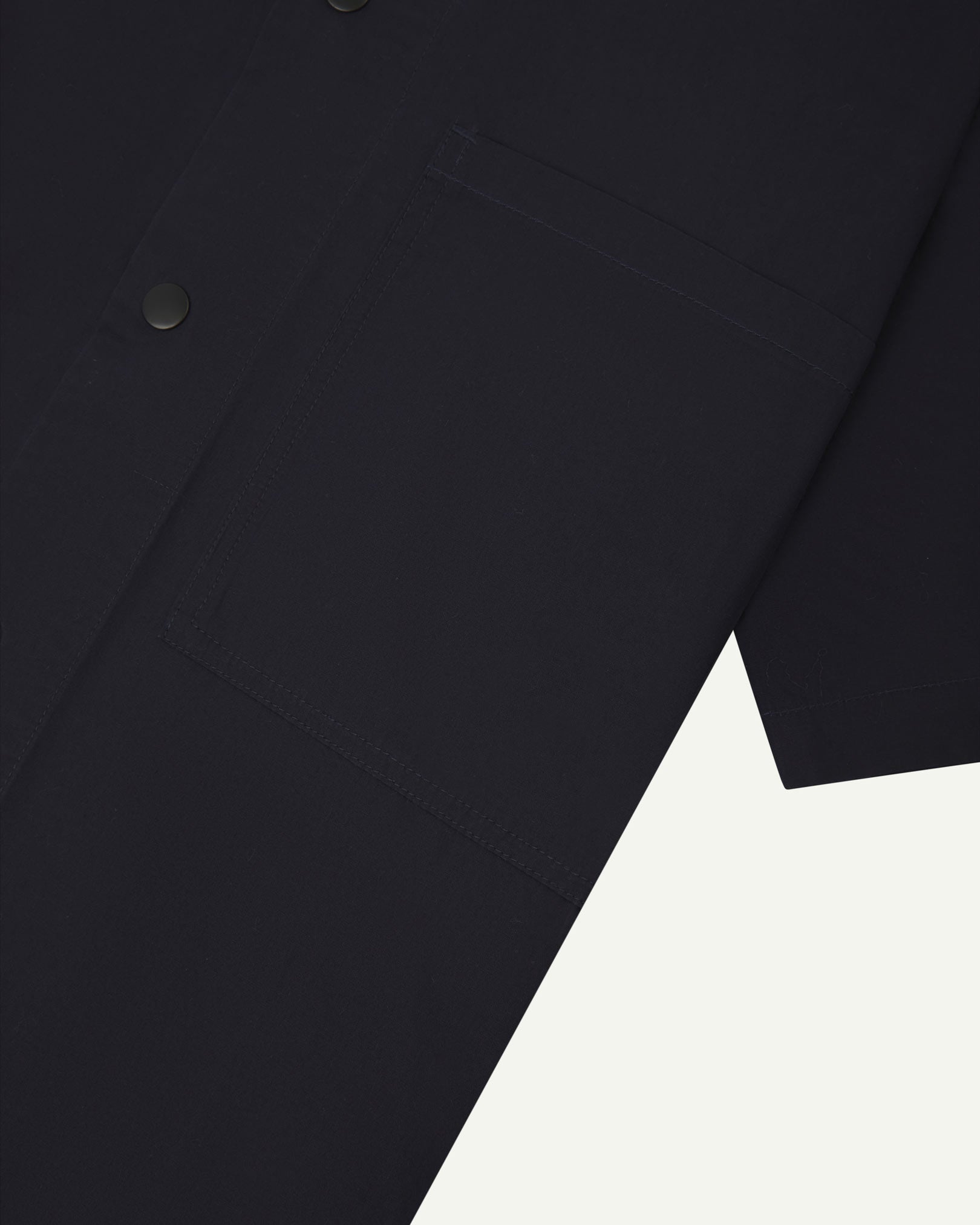 Angled mid-view of #6003 Uskees buttoned lightweight short sleeve shirt in midnight blue with focus on breast pocket.