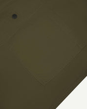 Angled mid-view of #6003 Uskees buttoned lightweight short sleeve shirt in olive-green with focus on breast pocket.