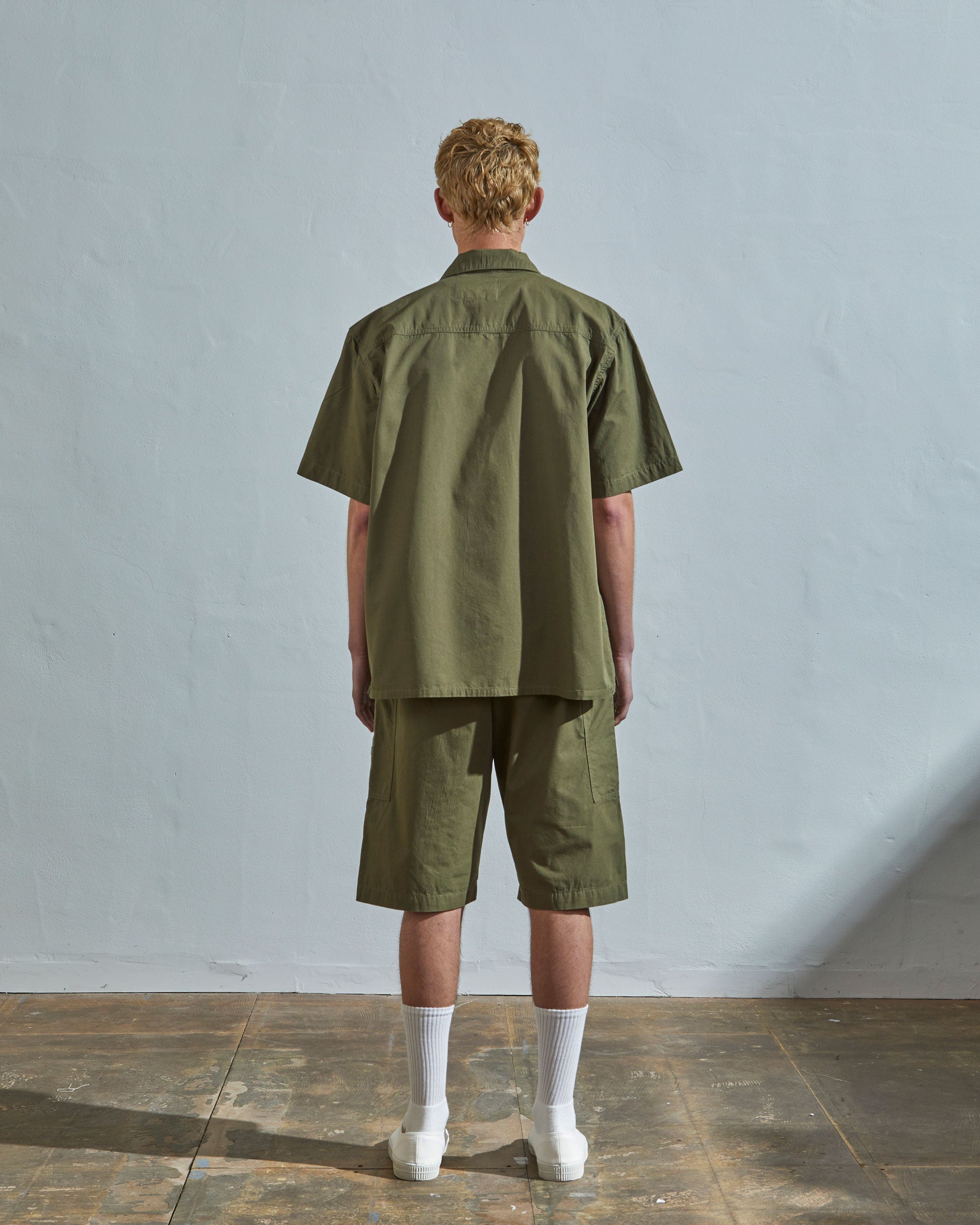 Full-length rear view of model wearing #6003 cotton shirt with matching lightweight olive shorts.