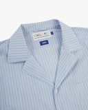 Close-up shot of Uskees blue, gold and white striped cuban shirt with focus on the notched collar, brand label and hanging loop.