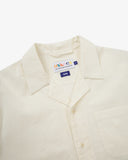 Close-up shot of Uskees off-white Cuban linen blend shirt with focus on the notched collar, brand label and hanging loop.