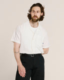 Top-half view of model wearing an Uskees off-white Cuban linen blend shirt demonstrating relaxed, casual fit.