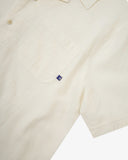 Close up view of Uskees off-white Cuban linen blend shirt for men with focus on the chest pocket and Uskees label tab.