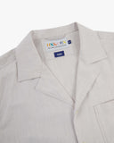 Close-up shot of Uskees off-white Cuban shirt with focus on the notched collar, brand label and hanging loop.