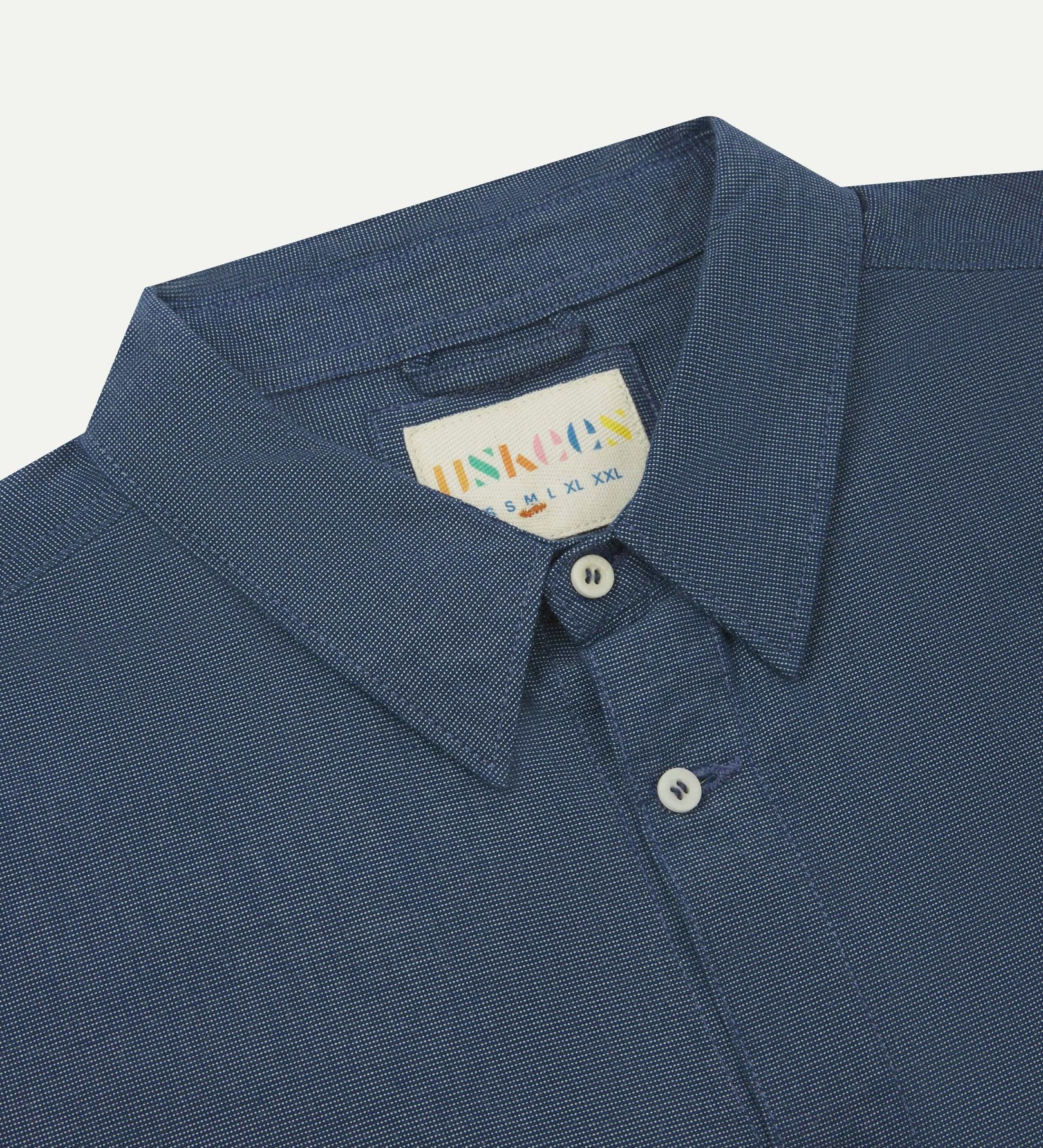 Close-up and angled front view of the 6006 Oxford shirt showing the texture of the breathable organic chambray Oxford cloth, collar and Uskees brand label.