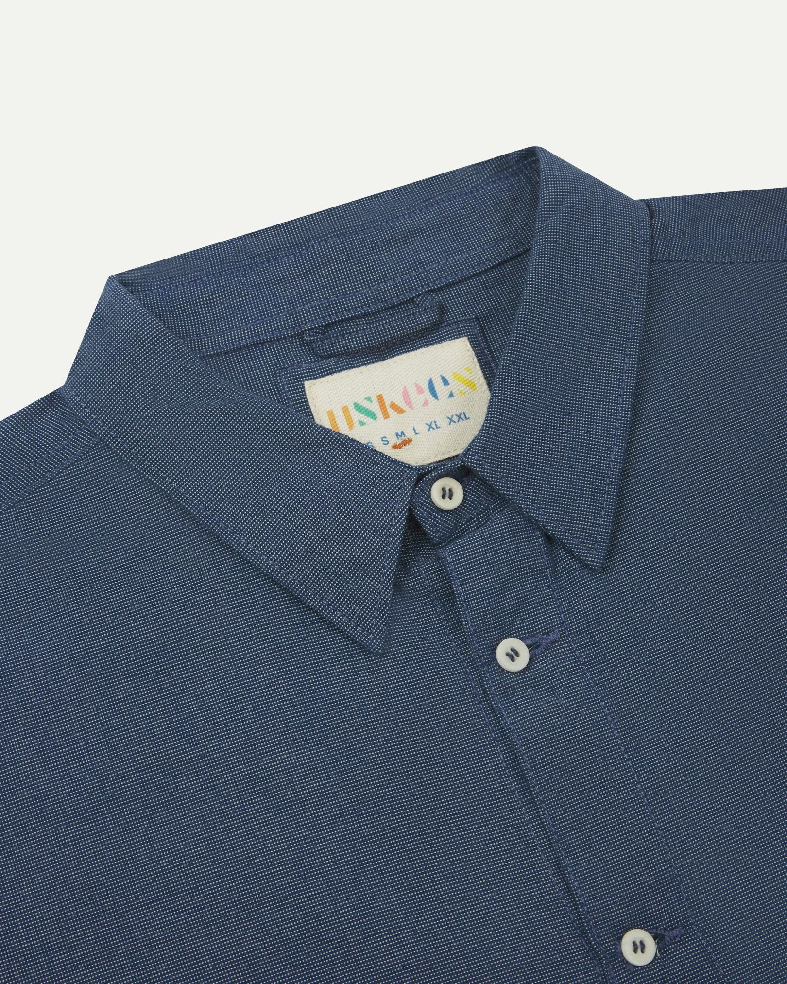 Close-up and angled front view of the 6006 Oxford shirt showing the texture of the breathable organic chambray Oxford cloth, collar and Uskees brand label.