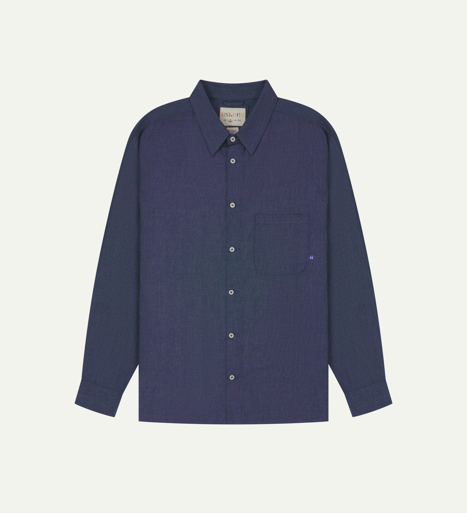 Flat front view of mid blue organic chambray Oxford shirt from Uskees. Clearly showing loose fit and 8-button front.