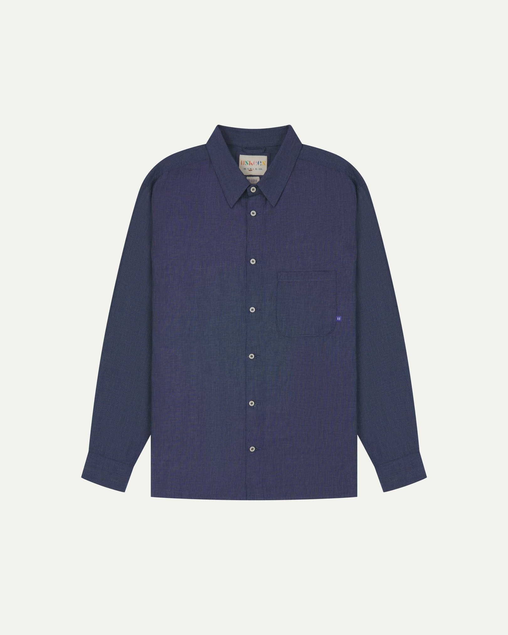 Flat front view of mid blue organic chambray Oxford shirt from Uskees. Clearly showing loose fit and 8-button front.