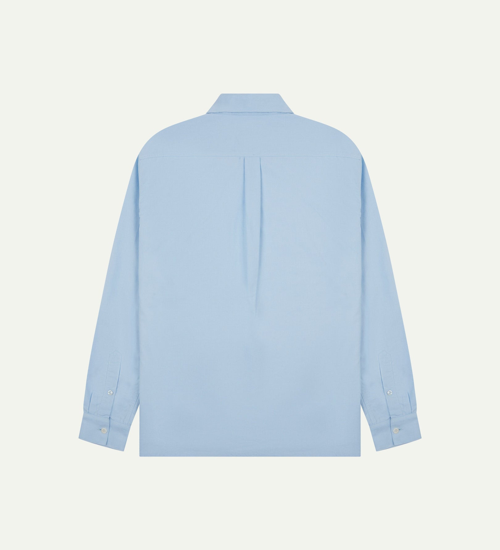 Flat back view of sky blue organic cotton Oxford shirt from Uskees with view of open pleat and longer rear hem so it can be tucked in more easily.