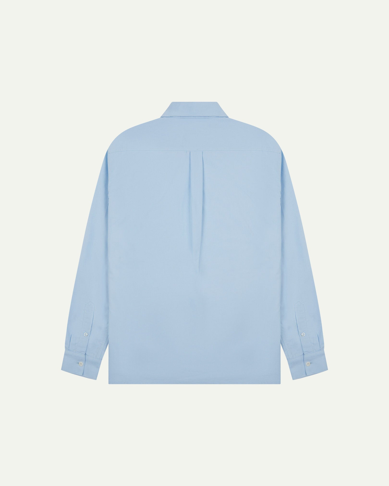 Flat back view of sky blue organic cotton Oxford shirt from Uskees with view of open pleat and longer rear hem so it can be tucked in more easily.