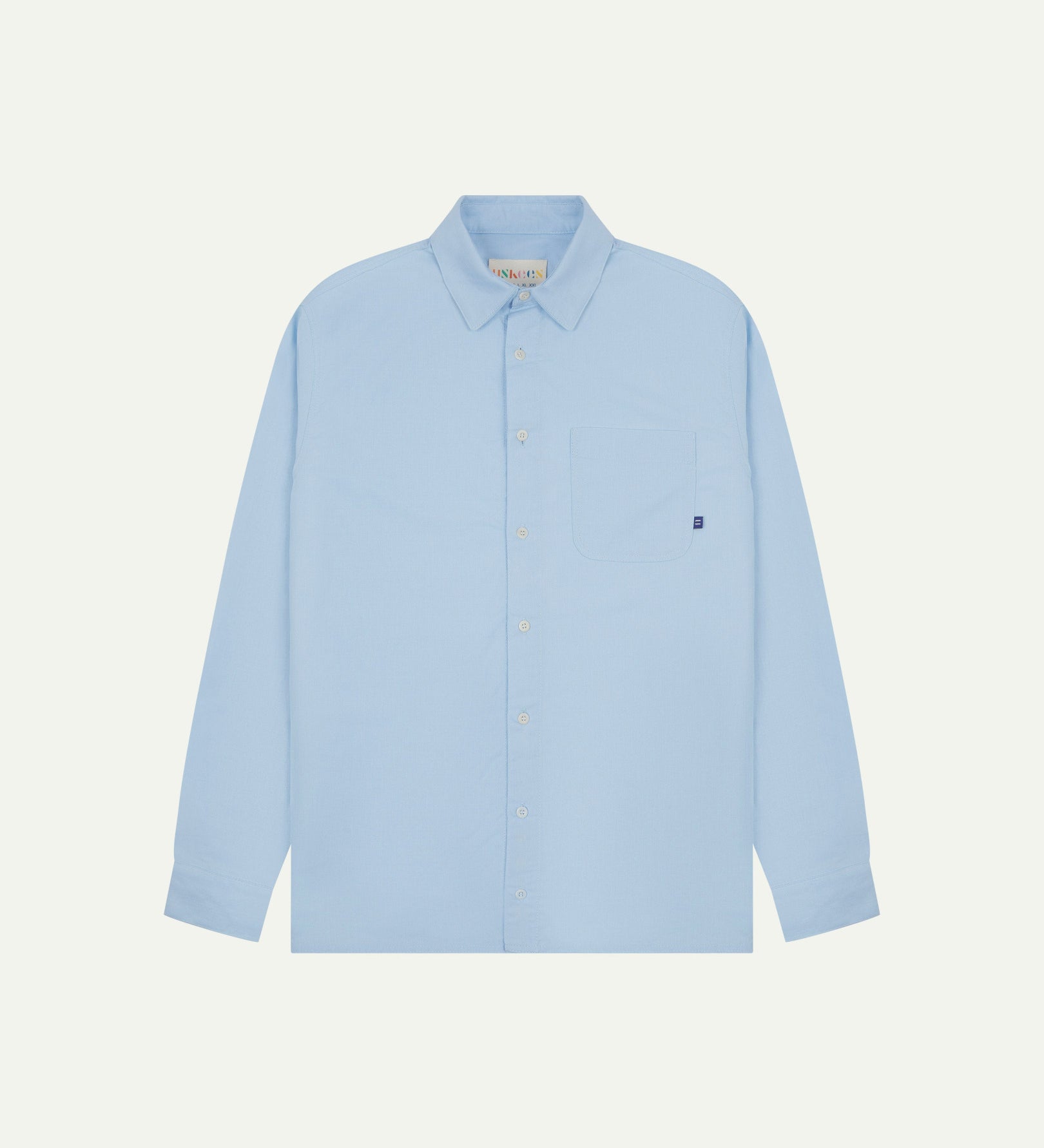 Flat front view of sky blue organic cotton Oxford shirt from Uskees. Clearly showing loose fit and 8-button front.