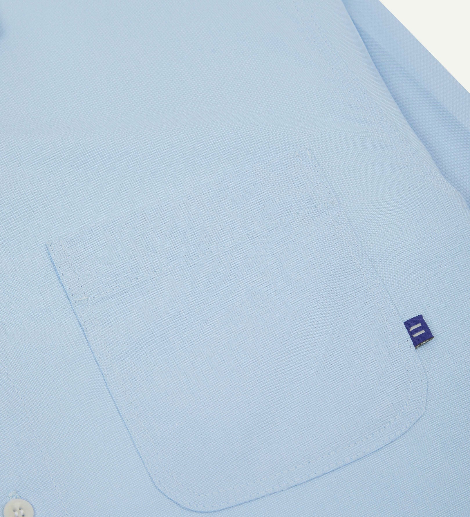 Close-up view of breast pocket of the 6006 Oxford shirt from Uskees with subtle branding. Also presented is a closer view of the texture of the organic cotton.