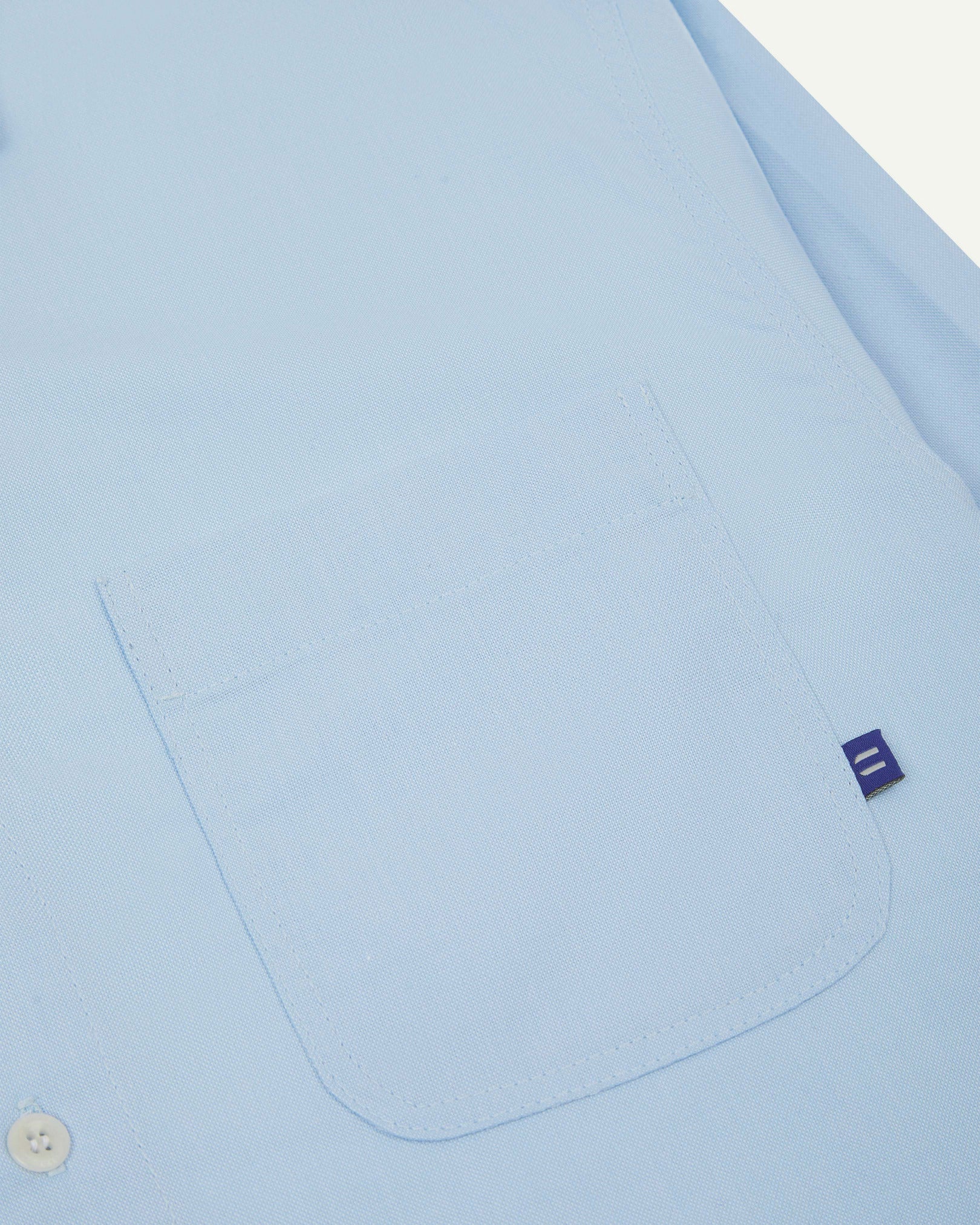 Close-up view of breast pocket of the 6006 Oxford shirt from Uskees with subtle branding. Also presented is a closer view of the texture of the organic cotton.