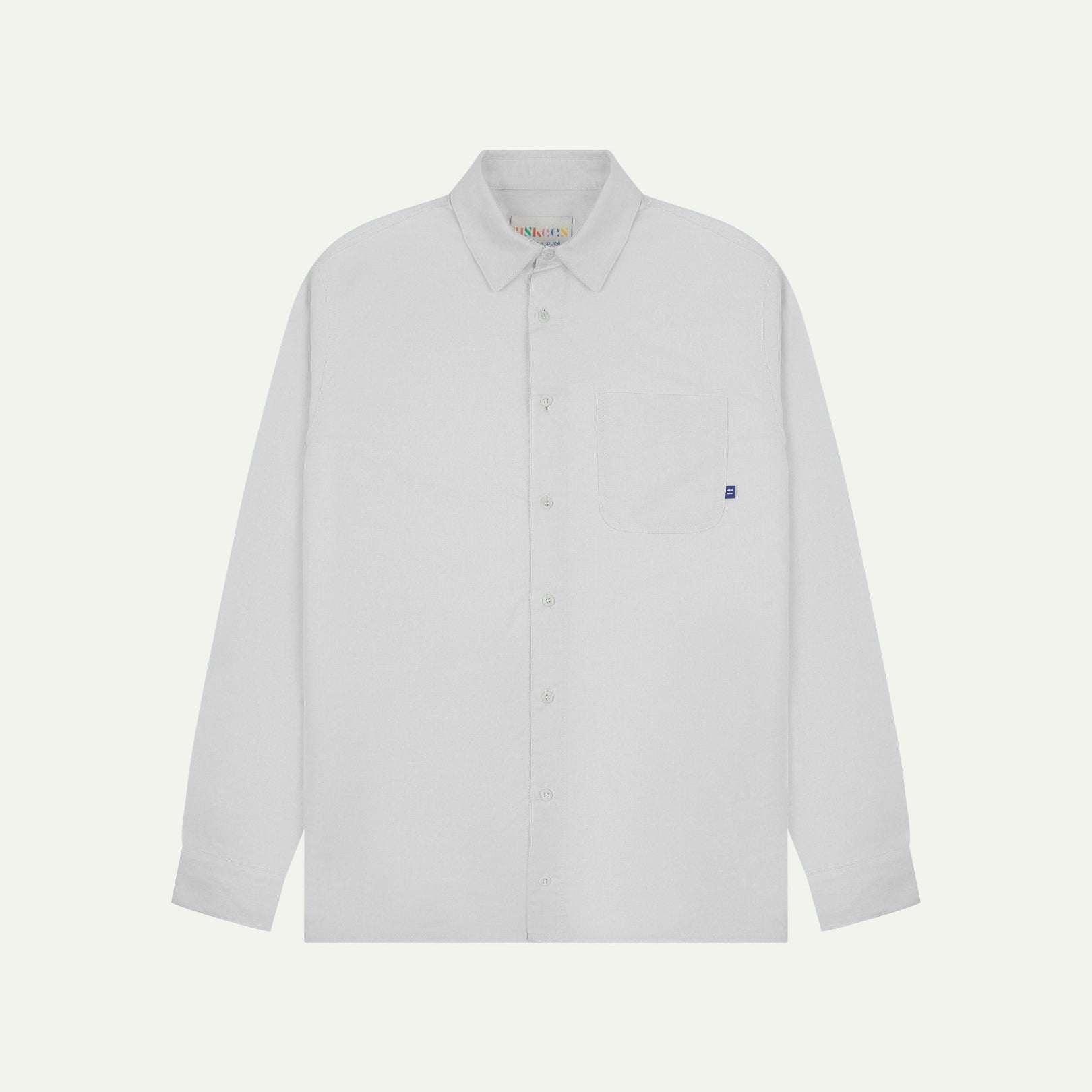 Flat front view of white organic cotton Oxford shirt from Uskees. Clearly showing loose fit and 8-button front.