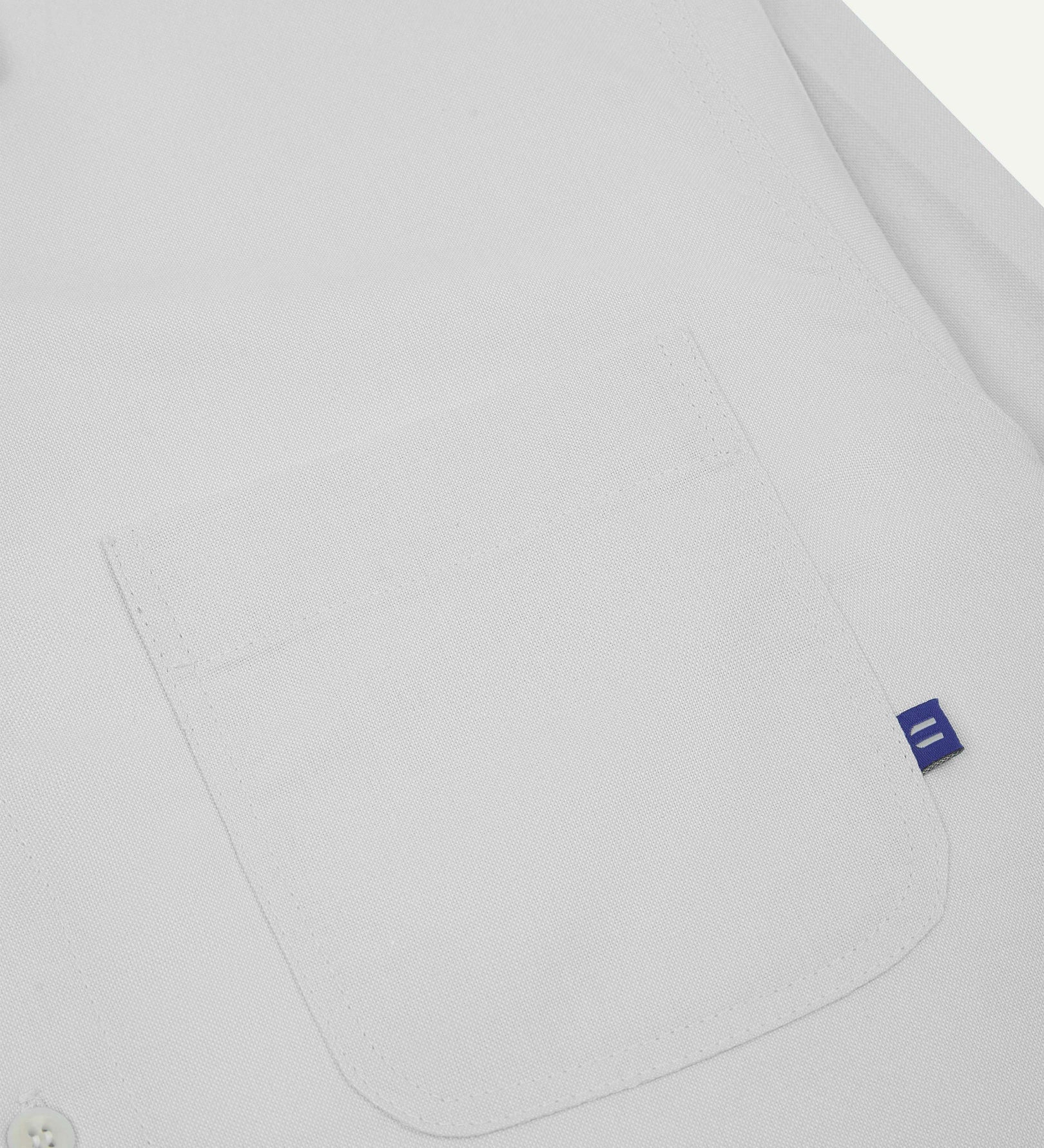 Close-up view of breast pocket of the 6006 Oxford shirt from Uskees with subtle branding. Also presented is a closer view of the texture of the organic cotton.