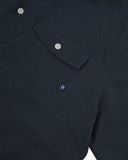 Angled mid-view of #6007 buttoned organic cotton dark blue short sleeve shirt with focus on button down flap chest pocket and Uskees branding tag.