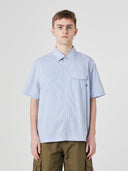 Top-half view of model wearing Uskees Tasker buttoned short sleeve shirt with blue, gold and white striped cotton fabric.