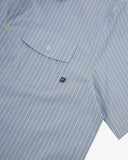 Angled mid-view of #6007 buttoned organic cotton blue, gold and white striped short sleeve shirt with focus on button down flap chest pocket and Uskees branding tag.