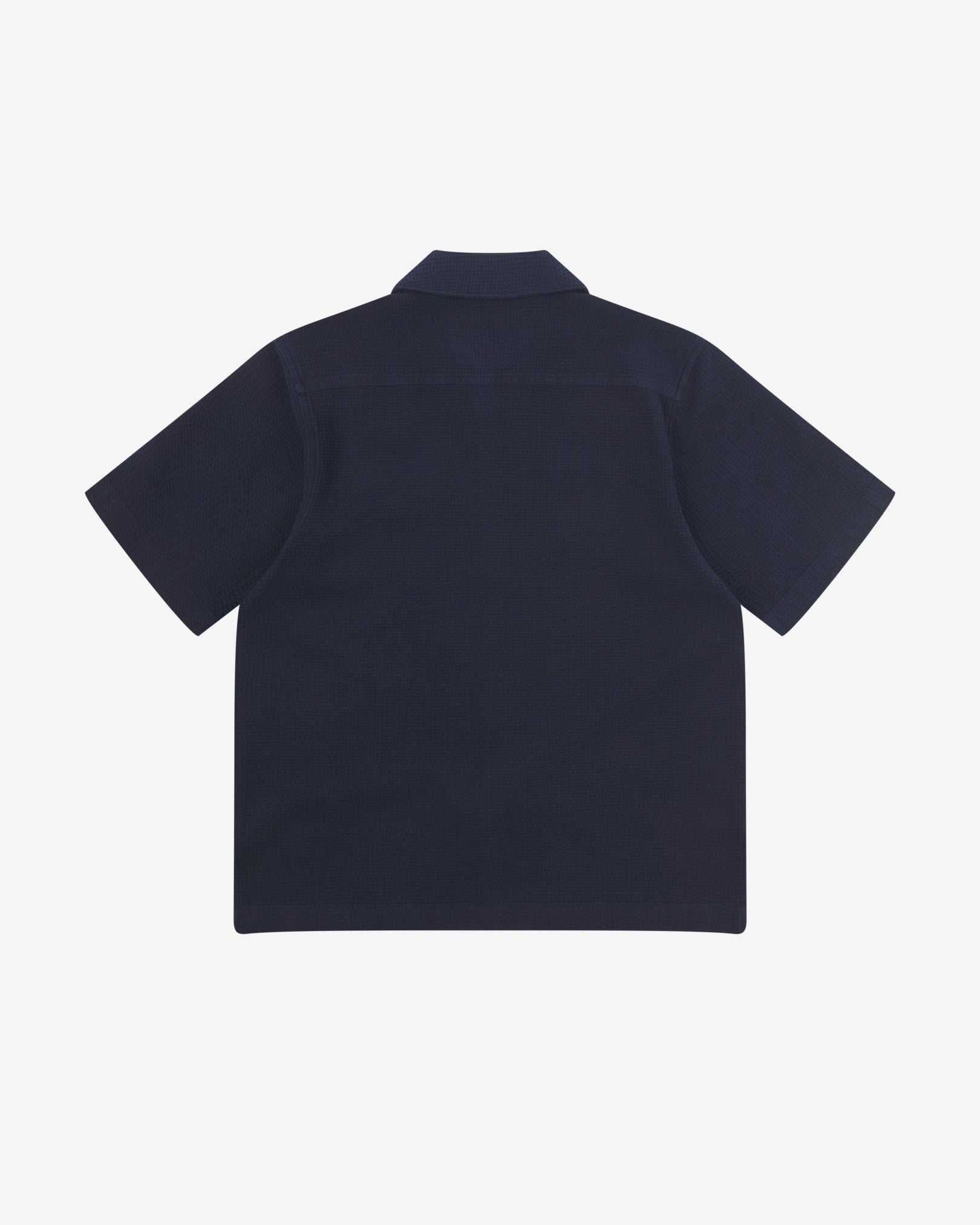 Reverse flat view of deep blue organic cotton waffle fabric short sleeve shirt from Uskees showing vent in hem and loose, relaxed silhouette.